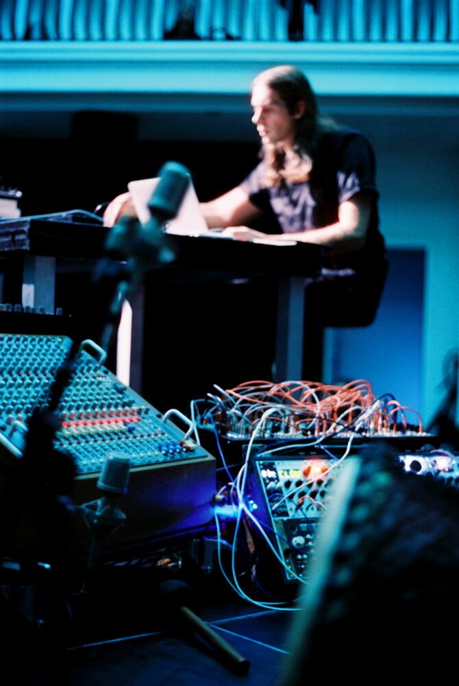Modular synth setup lit in blue, performer at laptop, Silent Green