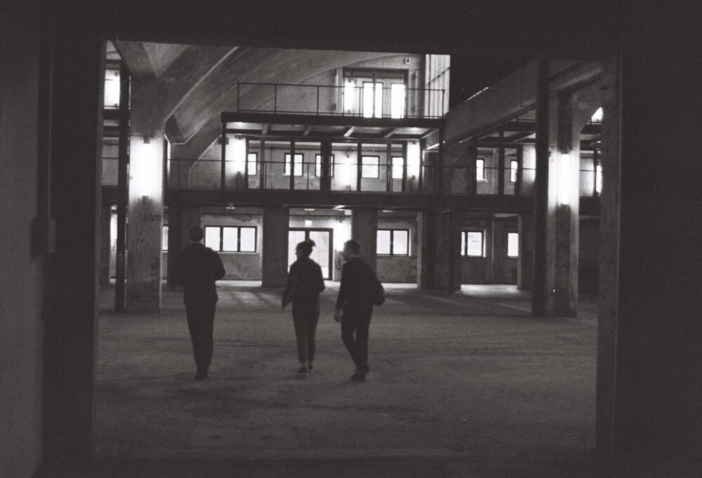 Monom, walking through the lit courtyard at night